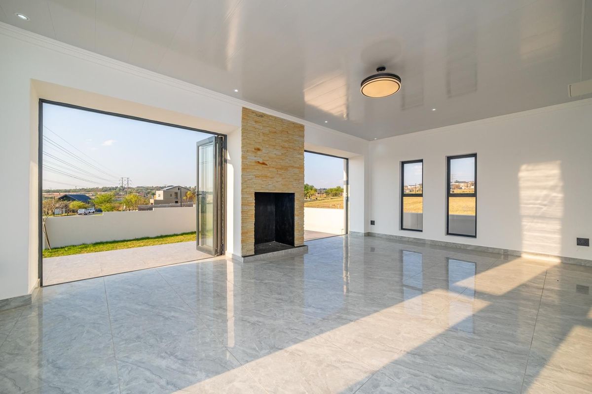 Spacious, modern living area featuring polished porcelain tiles, a stone-clad fireplace, and large bi-fold doors opening to an outdoor patio with scenic views.