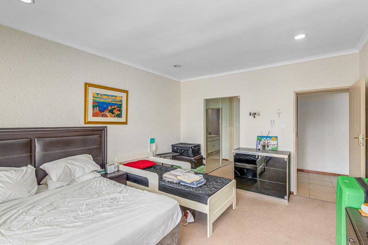 Spacious bedroom featuring neutral walls, recessed downlighting, and built-in cupboards with mirrored sliding doors, offering a functional layout.