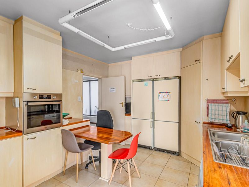 A functional kitchen featuring light-toned laminate cabinetry, wooden countertops, a built-in oven, and a stainless steel sink, requiring cosmetic updates to modernize the space.