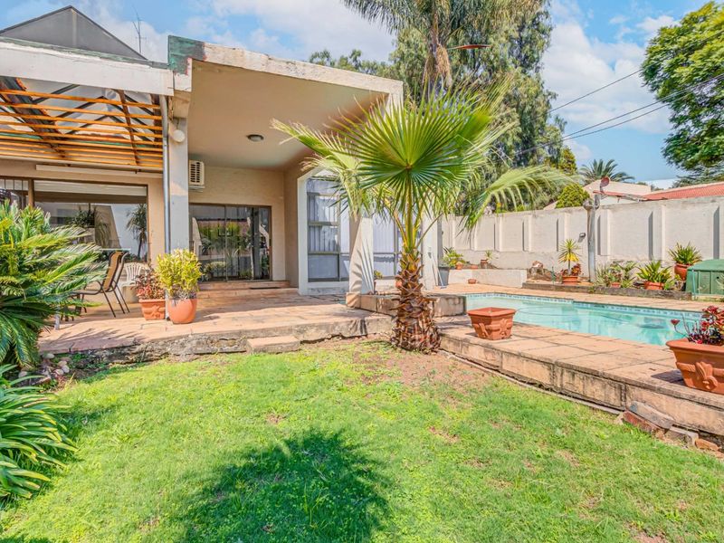 Outdoor pool area featuring a paved deck, covered patio with timber pergola, and perimeter walling, providing a functional space for outdoor relaxation.
