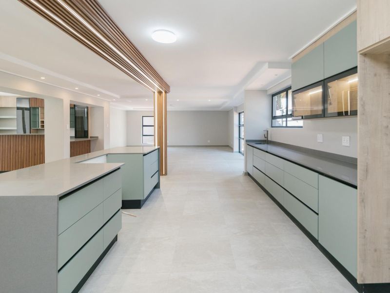 Modern, spacious kitchen featuring a large island, sleek cabinetry, quartz countertops, and a stylish timber slat ceiling detail in an open-plan layout.