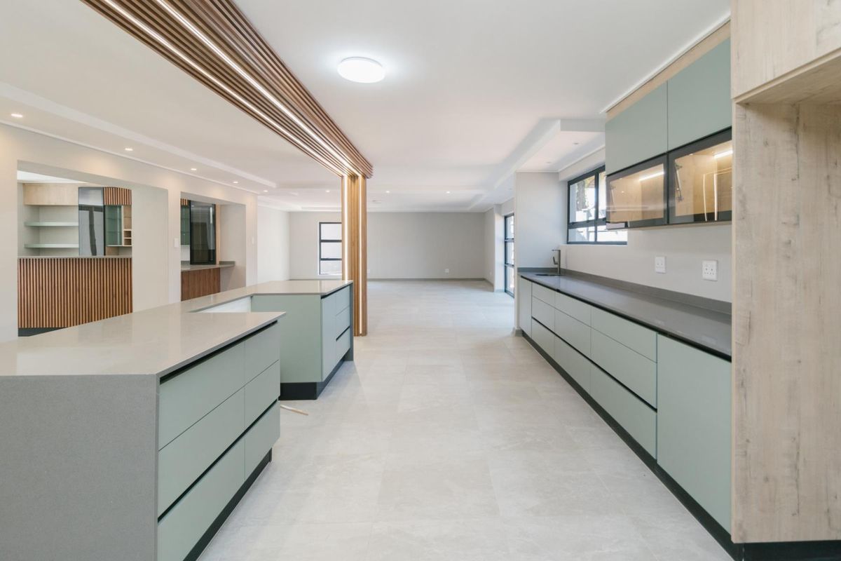 Modern, spacious kitchen featuring a large island, sleek cabinetry, quartz countertops, and a stylish timber slat ceiling detail in an open-plan layout.