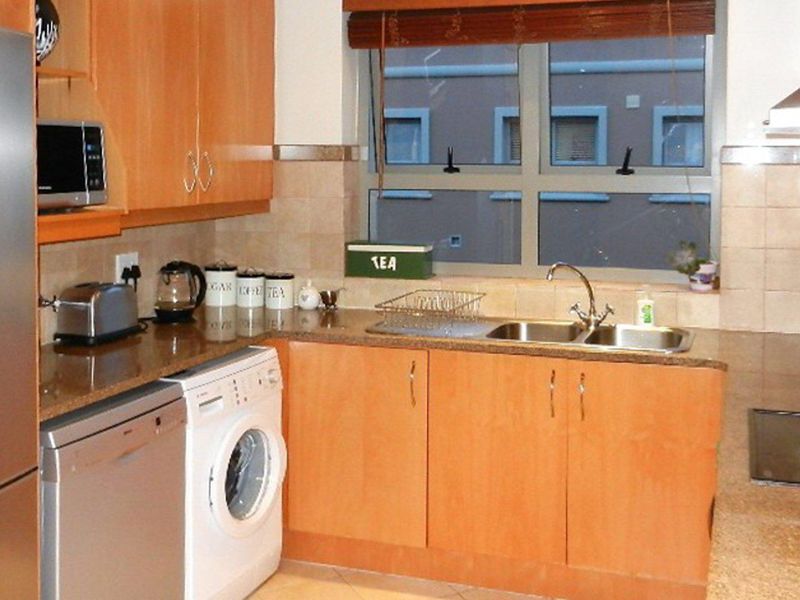 Functional kitchen featuring laminate cabinetry, granite countertops, a double bowl sink, and integrated appliances including a hob and extractor fan.