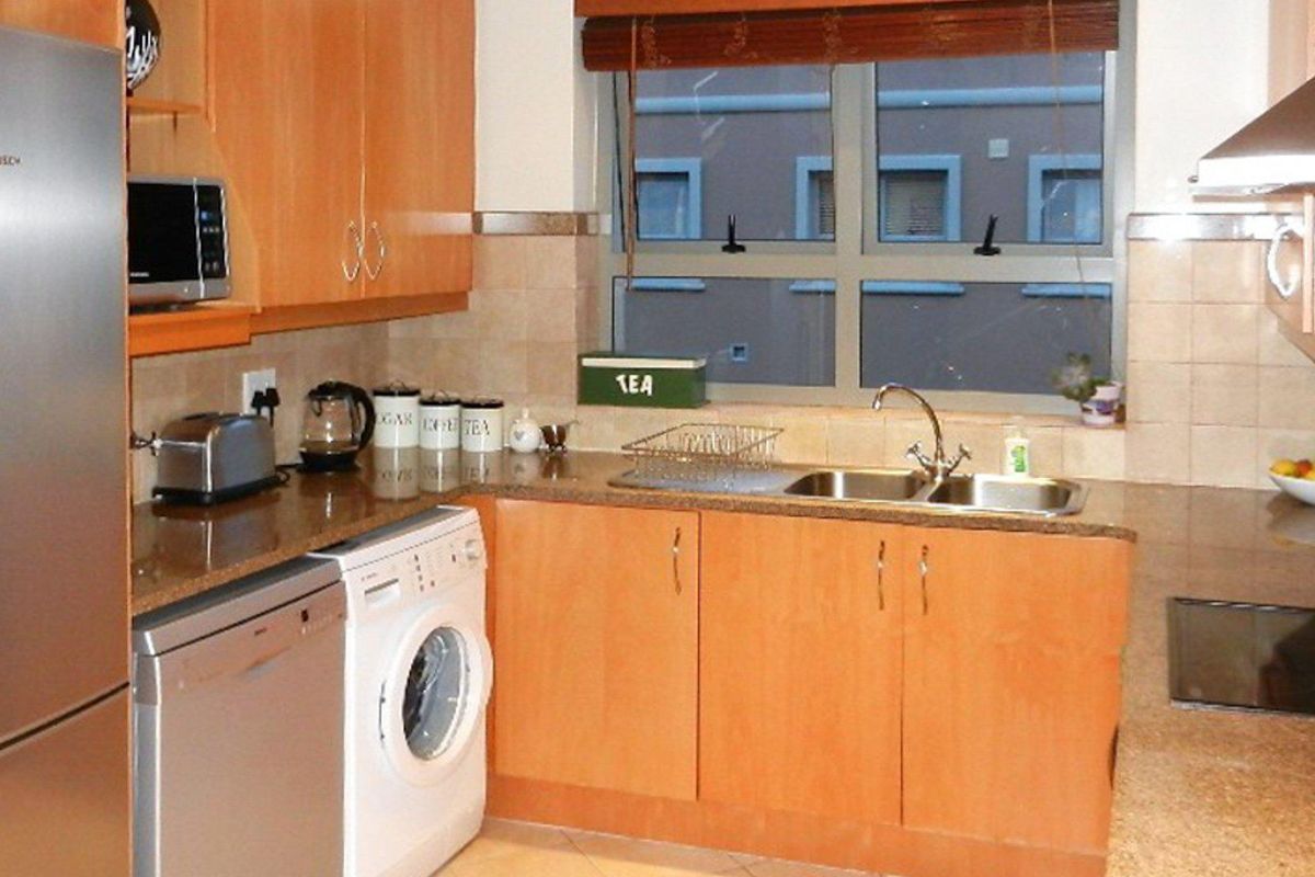 Functional kitchen featuring laminate cabinetry, granite countertops, a double bowl sink, and integrated appliances including a hob and extractor fan.