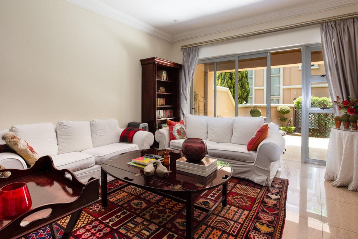 A bright living room featuring tiled flooring, crown molding, and large sliding glass doors that provide access to an outdoor patio area.