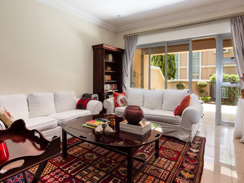 A bright living room featuring tiled flooring, crown molding, and large sliding glass doors that provide access to an outdoor patio area.