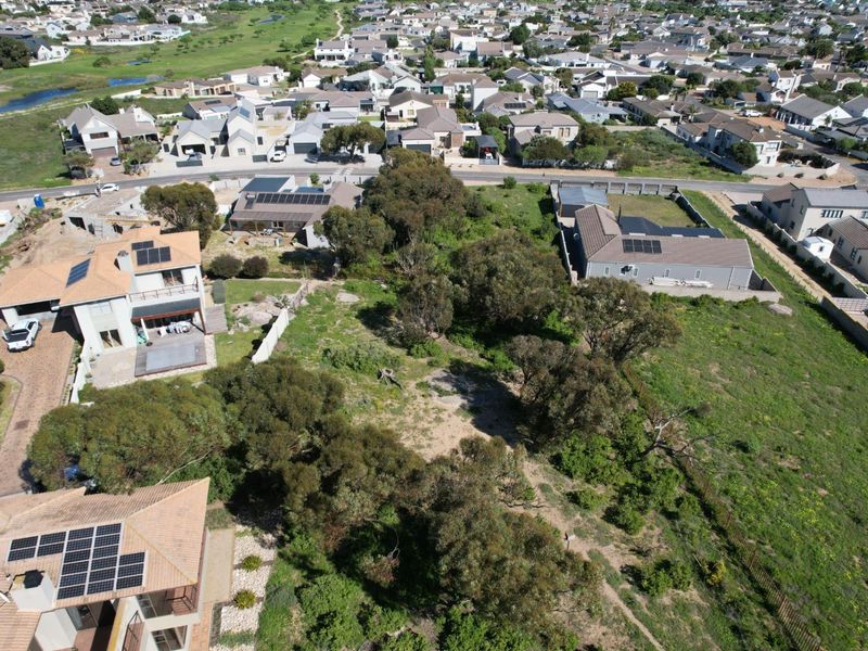 Aerial view of a vacant residential plot surrounded by established homes and mature trees in a suburban neighborhood.