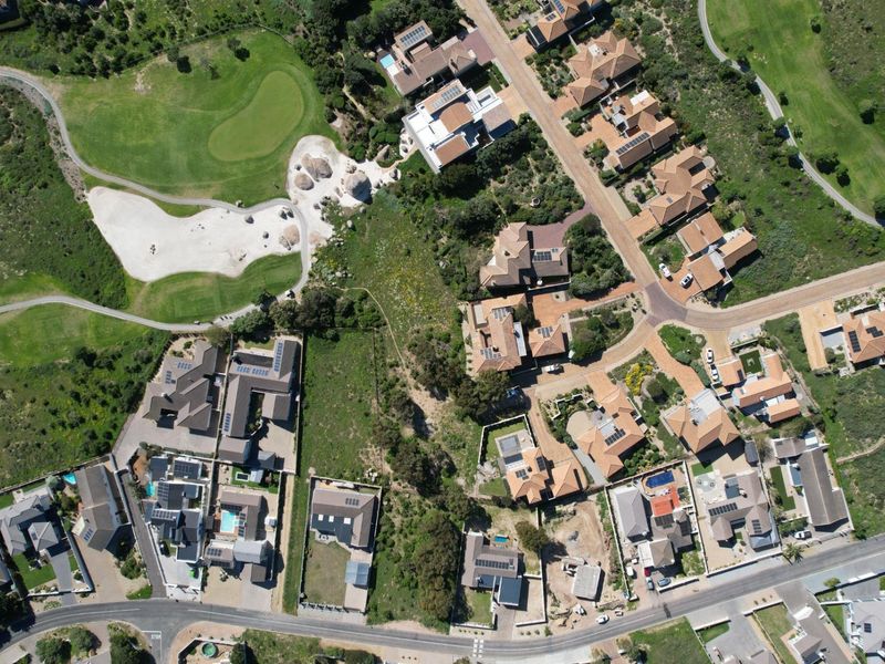 An aerial view of a residential estate featuring established homes, paved road networks, and adjacent golf course fairways.