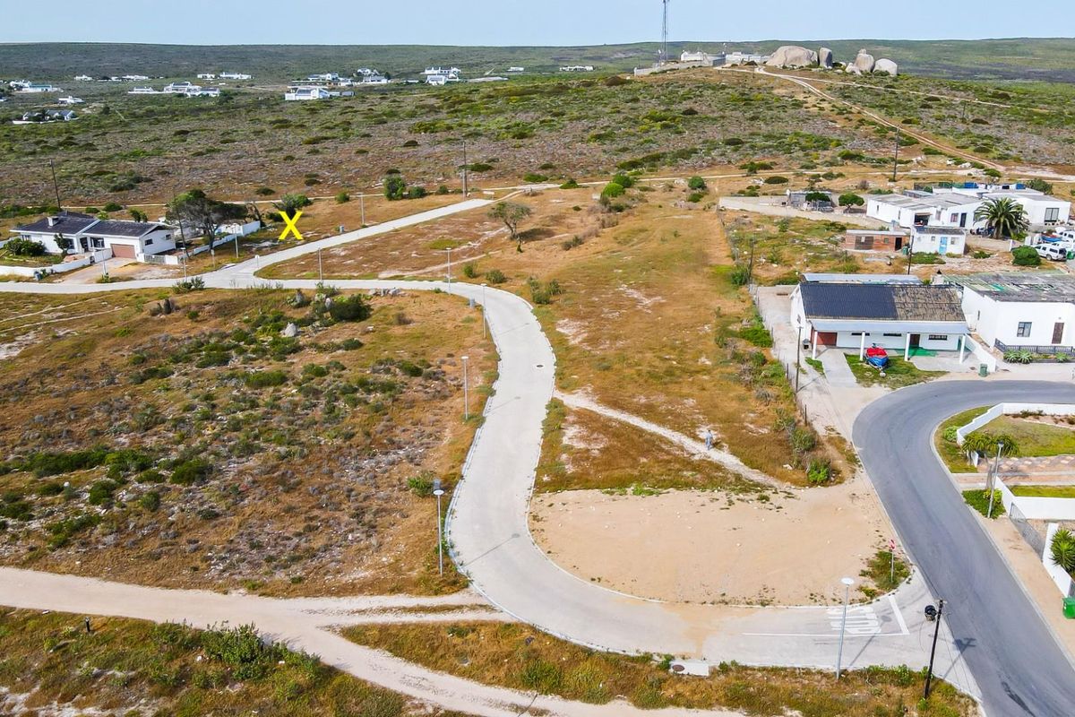 Aerial view of a residential vacant land plot situated in a coastal development with established road infrastructure and street lighting.