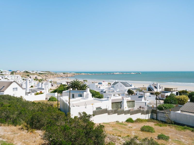 A scenic elevated view overlooking a coastal residential neighborhood with white-walled homes and direct access to the beach and ocean.