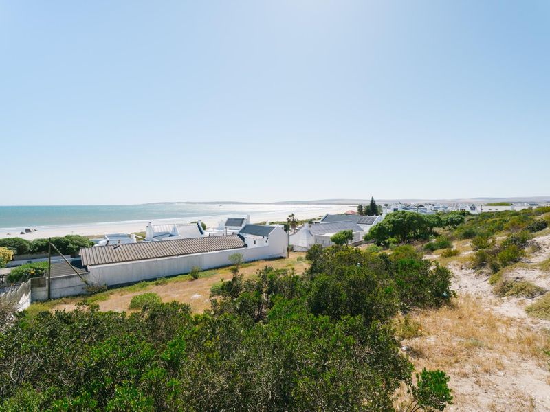 A scenic elevated view overlooking the coastline, sandy beach, and surrounding residential properties.