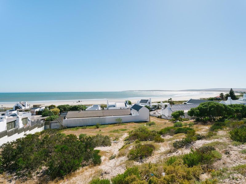 A scenic elevated view overlooking the coastal landscape, sandy beach, and ocean, showcasing the property's prime location near the shoreline.
