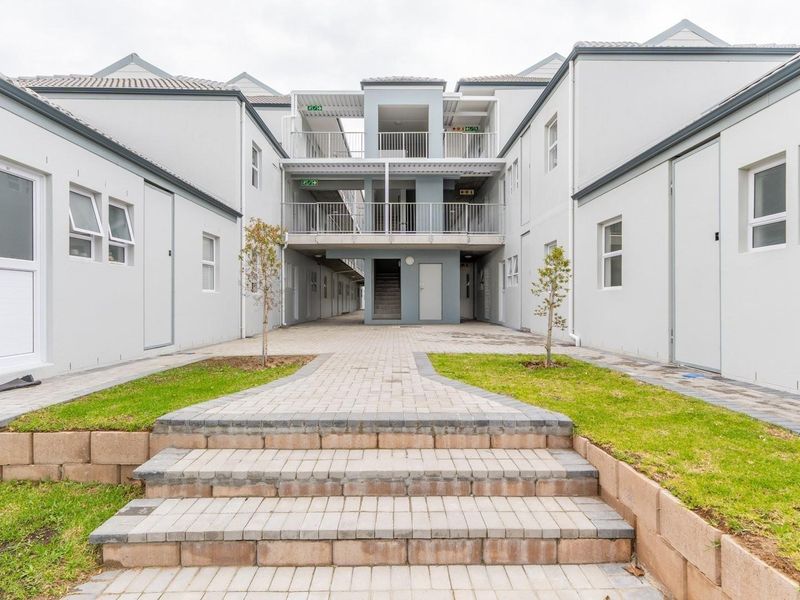 A view of the apartment complex courtyard featuring paved walkways, landscaped grass areas, and multi-level balcony access.