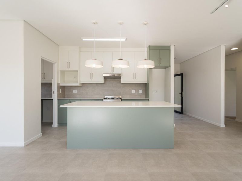 Modern kitchen featuring a central island, sleek cabinetry, stone countertops, and a tiled backsplash, offering a clean and functional culinary space.