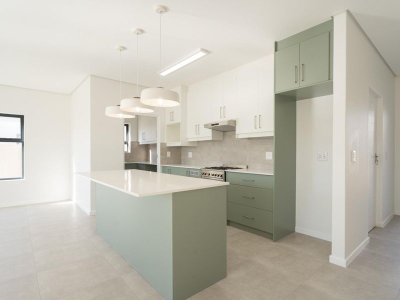 Modern kitchen featuring a central island, sage green and white cabinetry, quartz countertops, and integrated gas stove with extractor fan.
