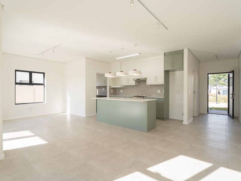 Spacious open-plan living and kitchen area featuring modern cabinetry, a central island, tiled flooring, and abundant natural light.