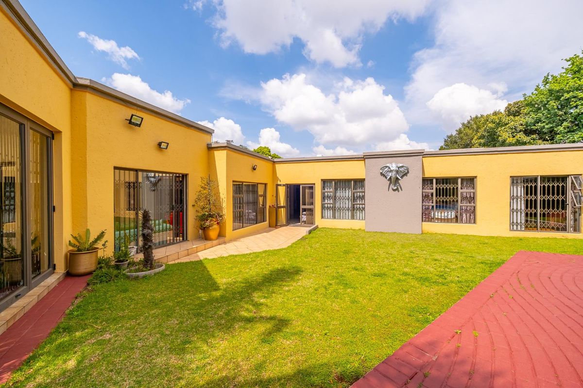 A well-maintained rear courtyard featuring a central lawn, paved pathways, and secure sliding door access to the main house structure.
