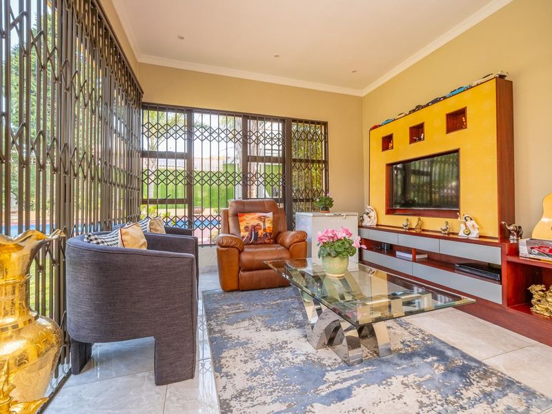 A bright living room featuring tiled flooring, recessed downlights, and a custom built-in media unit with integrated shelving.