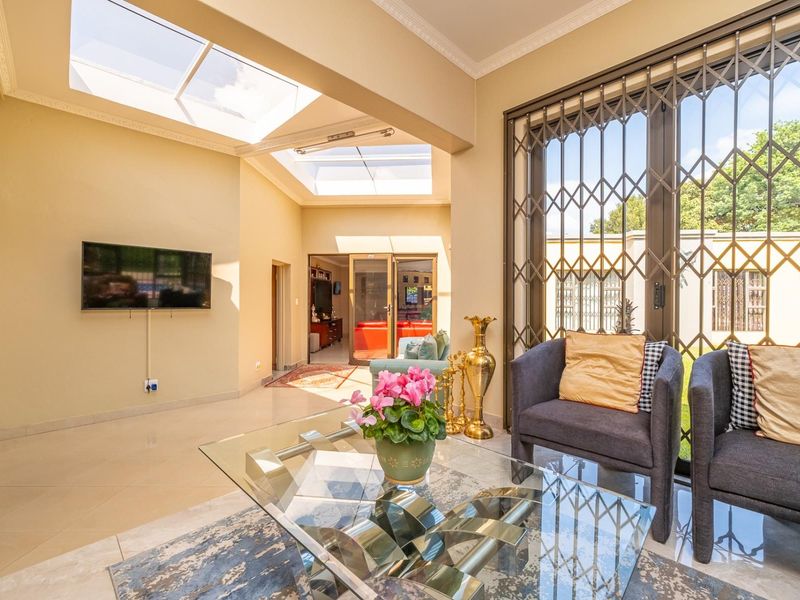 Bright living area featuring large skylights, tiled flooring, and secure sliding glass doors leading to the exterior.