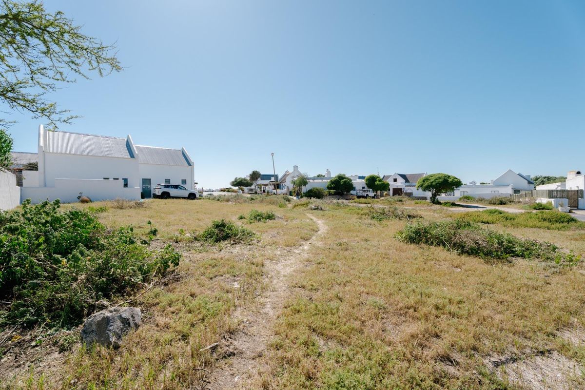 A view of a vacant residential plot featuring natural vegetation and surrounding neighborhood homes.