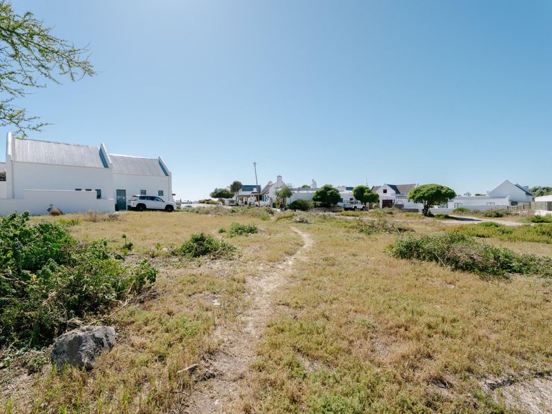 A view of a vacant residential plot featuring natural vegetation and surrounding neighborhood homes.