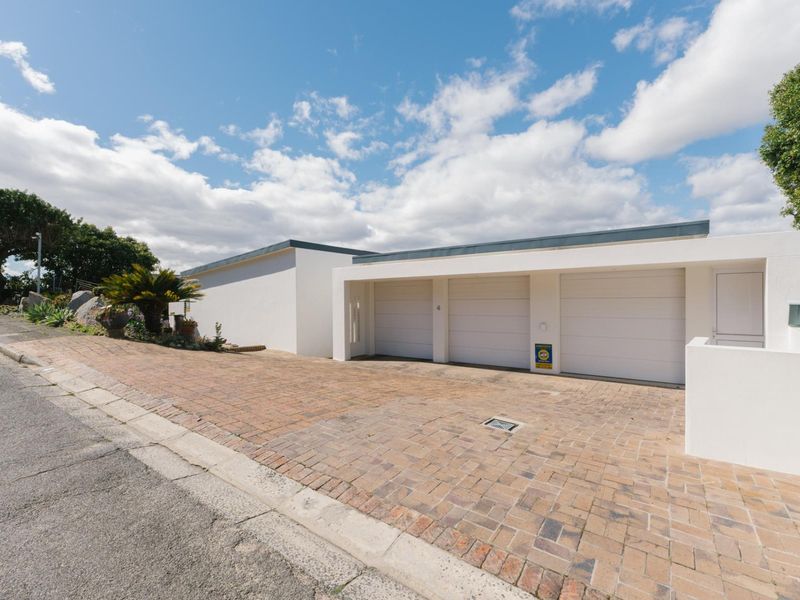 A modern exterior view of the property featuring a triple garage with white doors and a spacious paved driveway.
