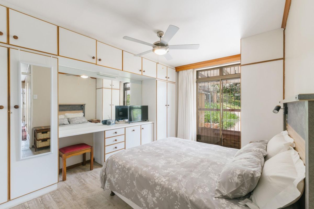 A bedroom featuring extensive built-in cabinetry, a vanity area, ceiling fan, and sliding glass doors providing access to the exterior.