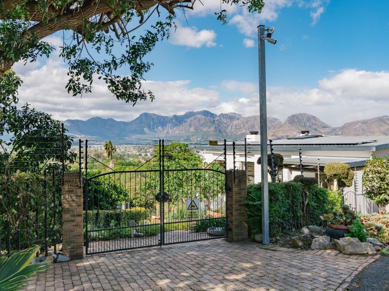 Front entrance featuring a secure gated driveway with electric fencing, security surveillance, and panoramic mountain views.