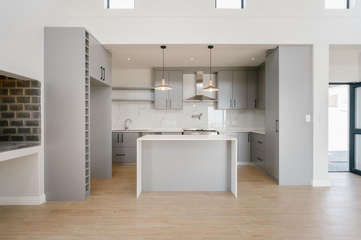 Modern kitchen featuring grey cabinetry, stone countertops, a central island, marble-look splashback, and high-quality finishes in an open-plan layout.