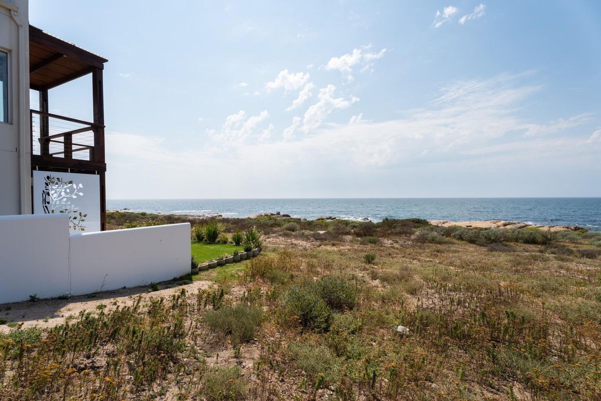A scenic view of the coastline and ocean from the property, featuring natural vegetation and a partial view of the building's balcony structure.