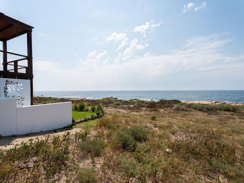 A scenic view of the coastline and ocean from the property, featuring natural vegetation and a partial view of the building's balcony structure.