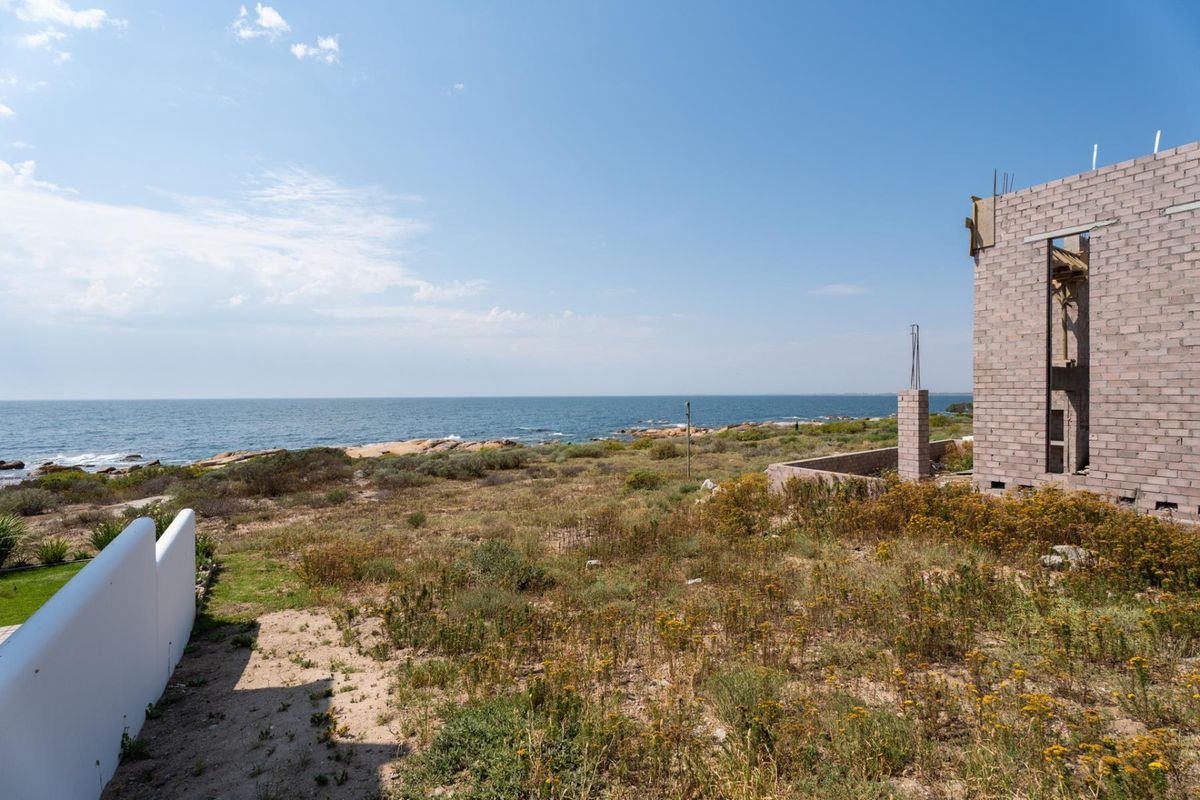 A scenic coastal view overlooking the ocean from a residential property featuring an unfinished masonry structure.