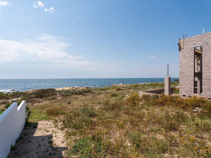 A scenic coastal view overlooking the ocean from a residential property featuring an unfinished masonry structure.