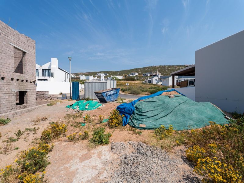 A view of a residential plot under construction, featuring an unfinished masonry structure and surrounding site development.