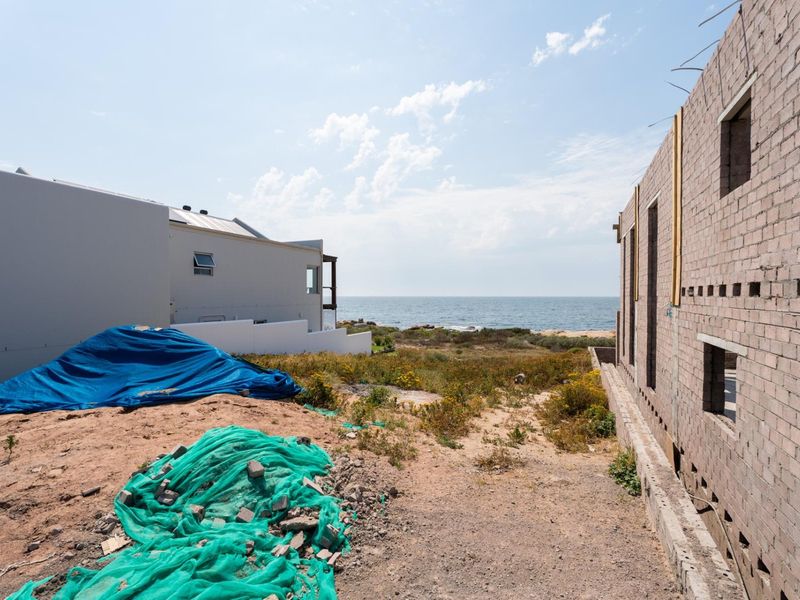 A view of a residential construction site featuring an unfinished brick structure with direct coastal views.