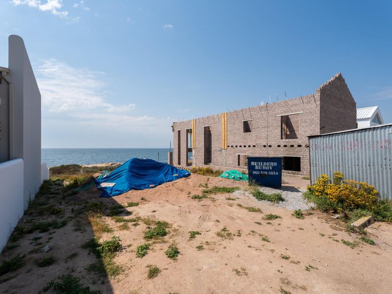 A view of a residential property under construction, featuring an exposed concrete block structure with ocean views.