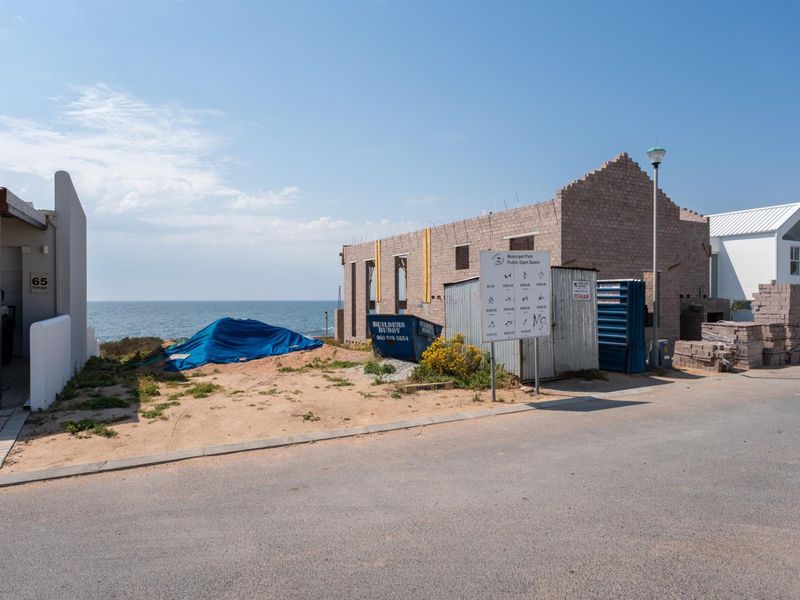 A vacant residential plot featuring an incomplete masonry structure with direct coastal views and street access.