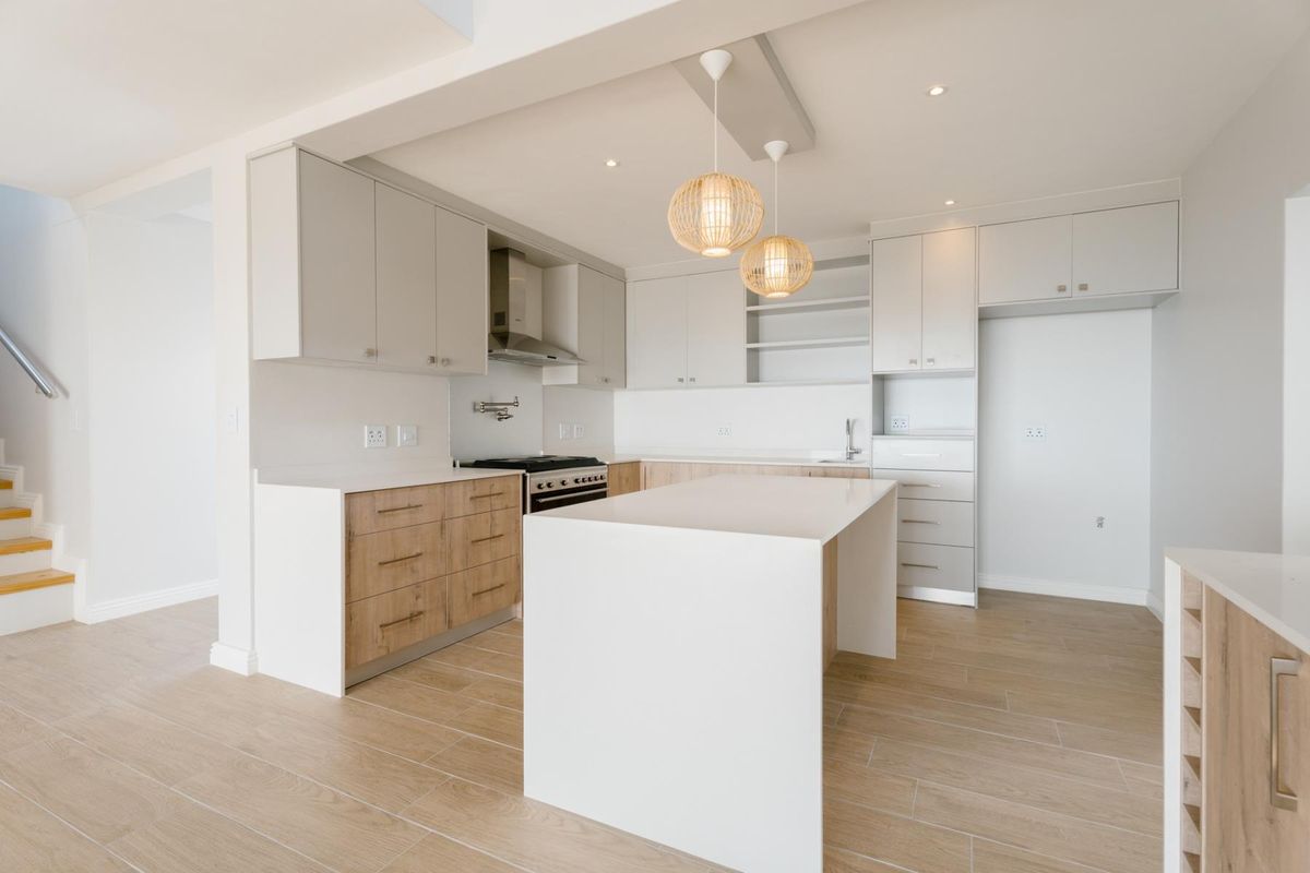 Modern, bright kitchen featuring a central island, sleek cabinetry, gas stove, and high-quality tiled flooring in an open-plan layout.