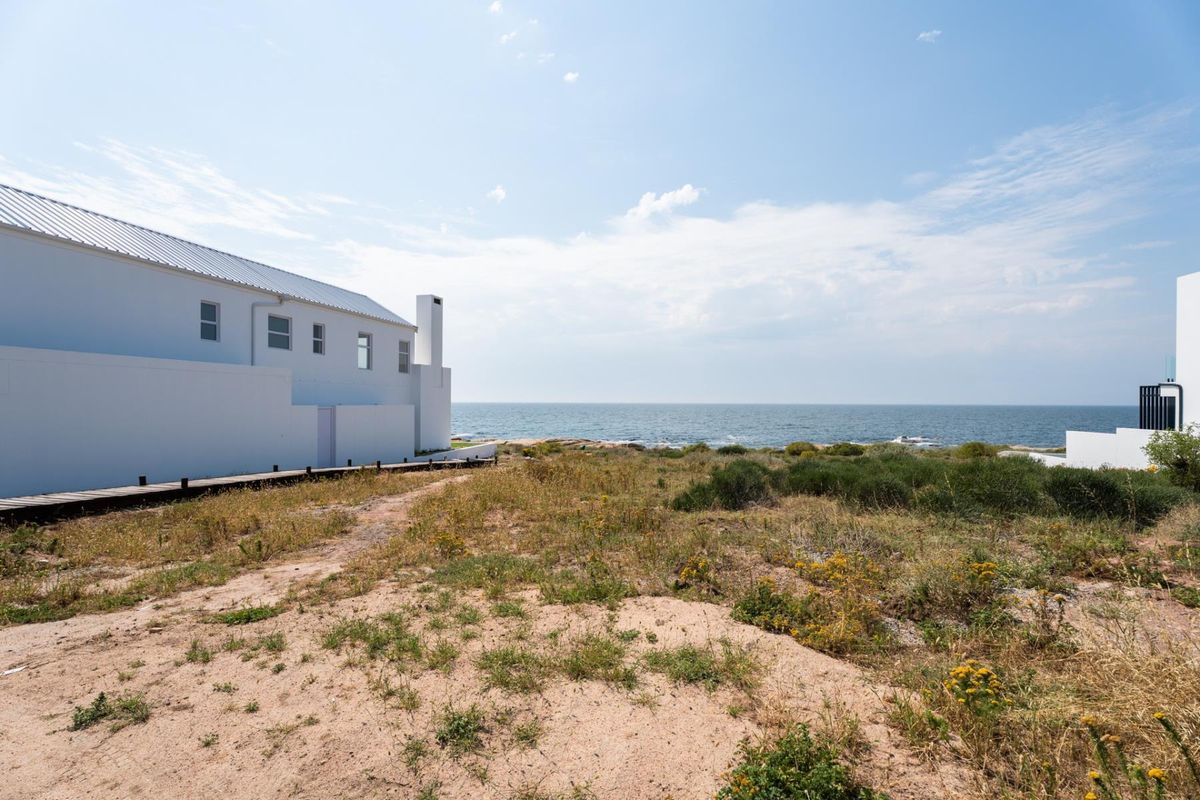 A view of the rear exterior of a coastal property featuring a wooden boardwalk leading towards the ocean.
