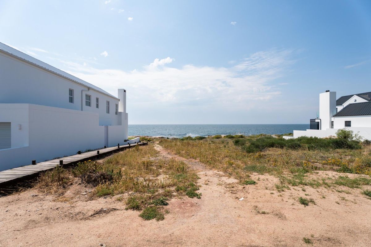 A scenic view of the ocean from a coastal residential property, featuring a wooden boardwalk leading towards the shoreline.