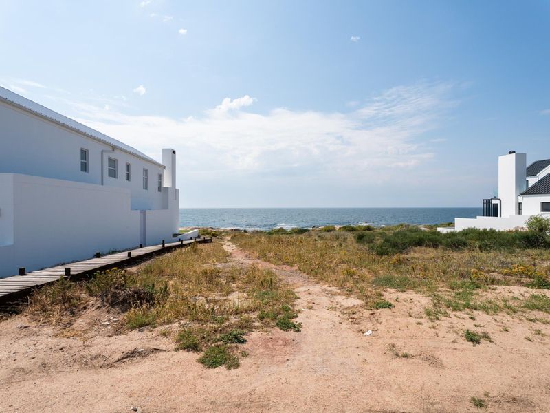 A scenic view of the ocean from a coastal residential property, featuring a wooden boardwalk leading towards the shoreline.