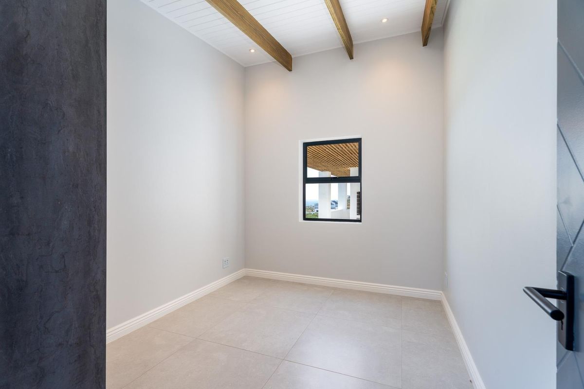 A bright, modern, and empty bedroom featuring exposed timber ceiling beams, neutral tiled flooring, and clean finishes, ready for personalization.