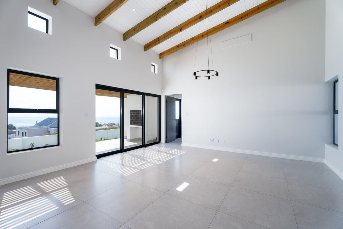 Spacious, light-filled living area featuring high vaulted ceilings with exposed timber beams, large format floor tiles, and sliding doors leading to an outdoor patio.