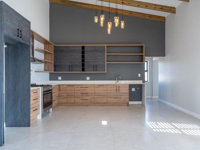 Modern kitchen featuring wood-grain and dark cabinetry, gas stove, extractor fan, and exposed timber beams under a high vaulted ceiling.