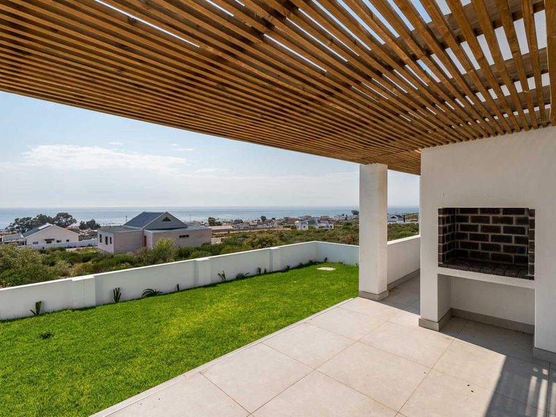 Covered patio featuring a timber pergola, built-in braai, and tiled flooring, offering expansive coastal and neighbourhood views.
