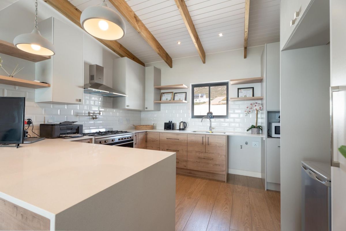 Modern kitchen featuring timber cabinetry, quartz countertops, subway tile backsplash, and exposed timber ceiling beams, creating a bright and contemporary culinary space.