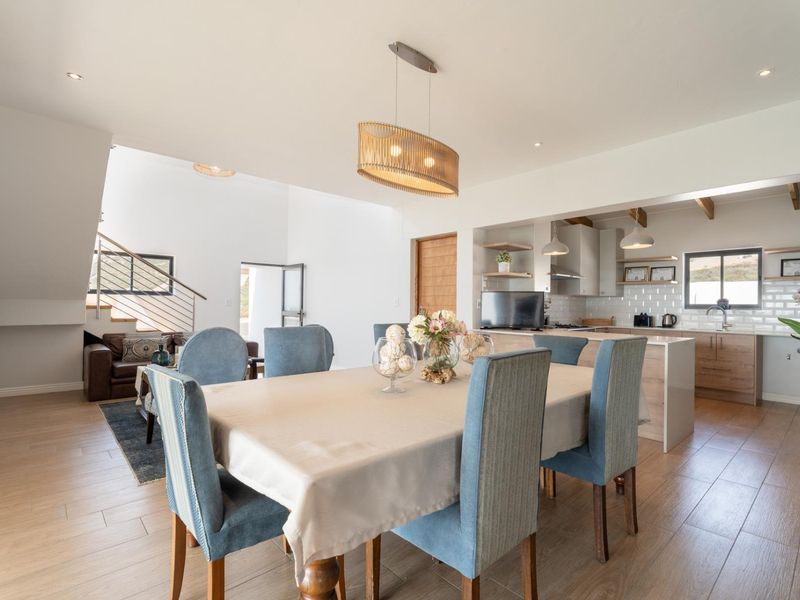 Spacious open-plan living and dining area featuring a modern kitchen with subway tile backsplash, island, and a staircase leading to the upper level.