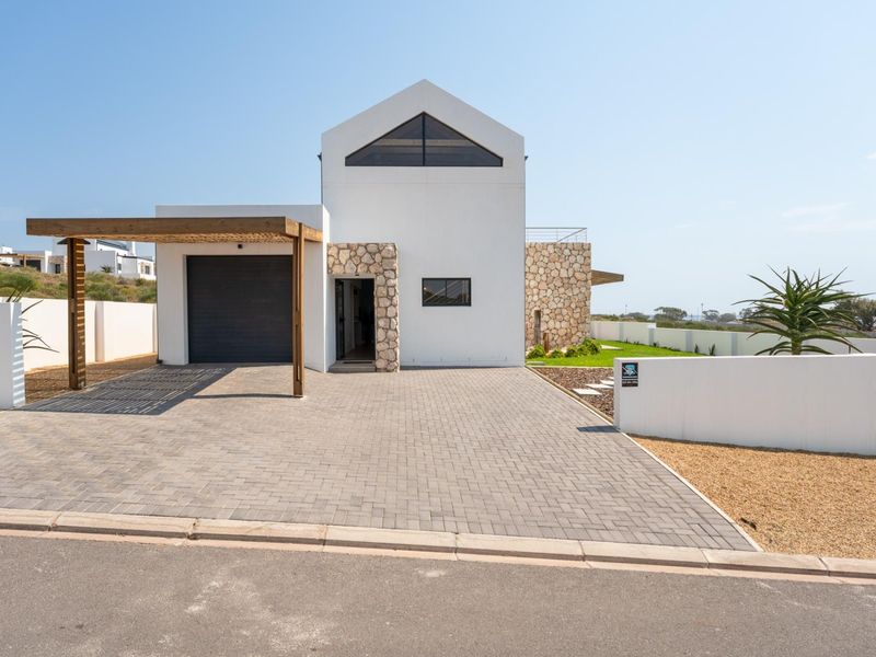 Modern architectural front elevation featuring stone cladding, a paved driveway, and a timber pergola over the garage entrance.