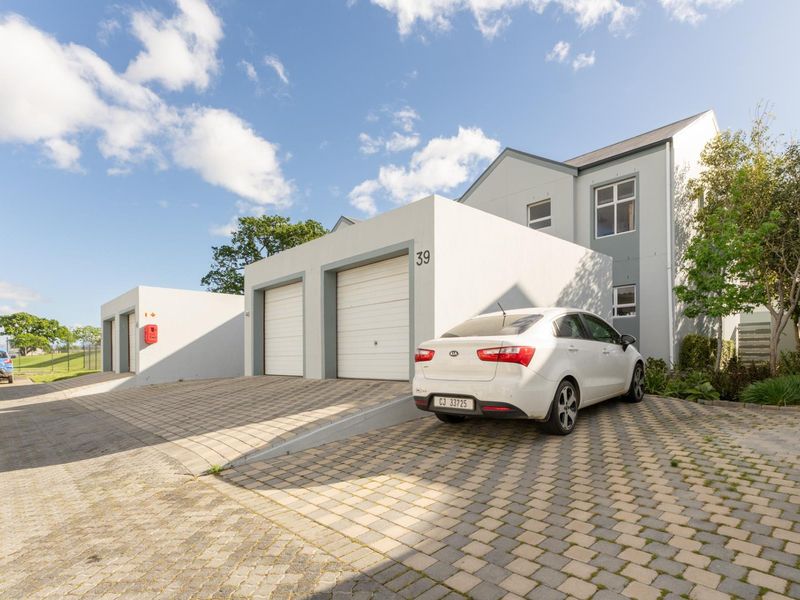 Front exterior view of a modern residential property featuring a double garage, paved driveway, and clean architectural lines.