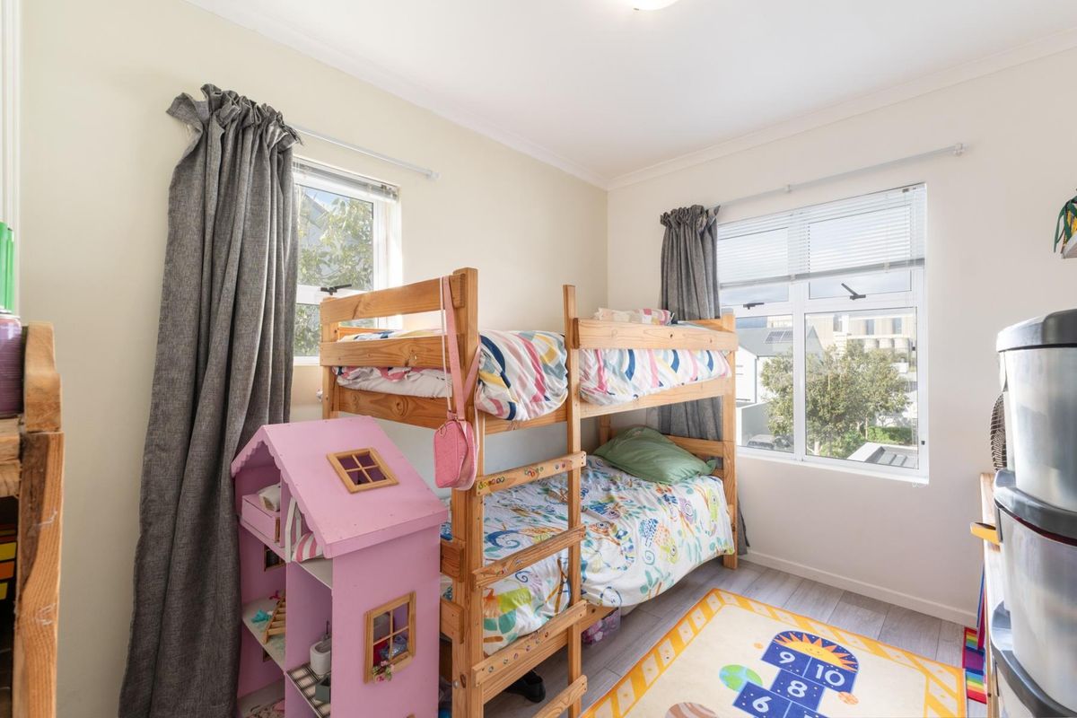 A functional bedroom featuring laminate flooring and dual windows with curtain tracks, providing natural light and a view of the surrounding area.